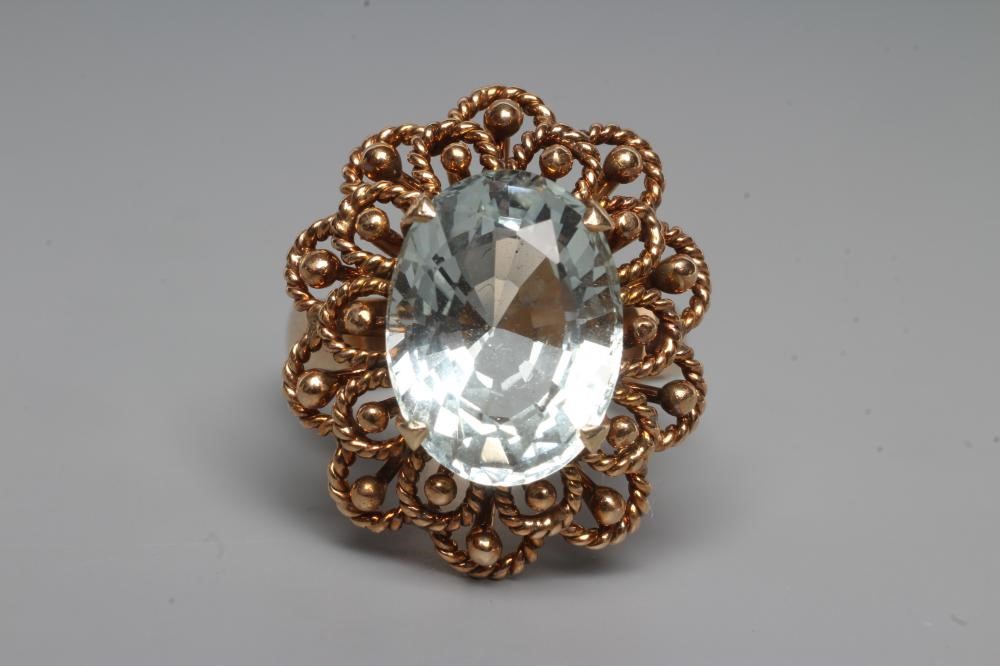 AN AQUAMARINE COCKTAIL RING, the oval facet cut stone claw set to a rope twist open border and plain Image