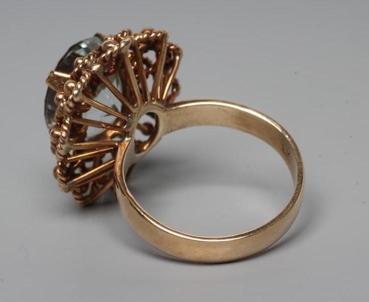 AN AQUAMARINE COCKTAIL RING, the oval facet cut stone claw set to a rope twist open border and plain Image