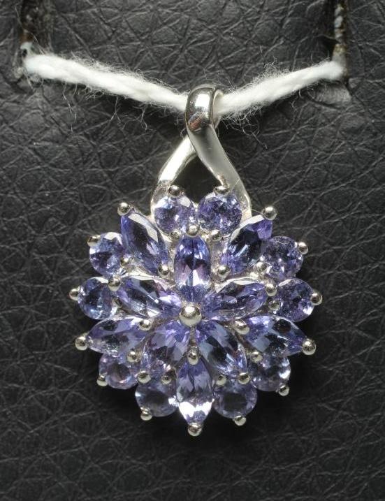 A TANZANITE CLUSTER PENDANT, the circular and marquise cut stones point set to a plain 9ct white Image