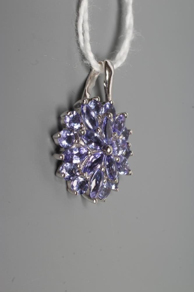 A TANZANITE CLUSTER PENDANT, the circular and marquise cut stones point set to a plain 9ct white Image
