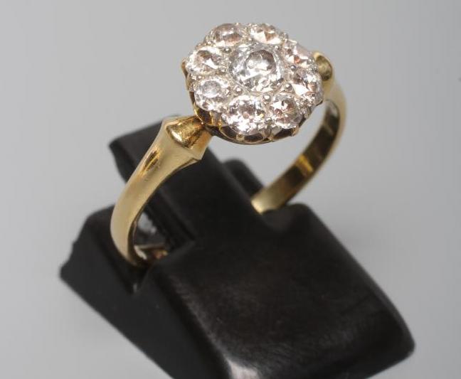 A NINE STONE DIAMOND CLUSTER RING, the old brilliant cut stones set to a plain shank stamped 18ct, Image