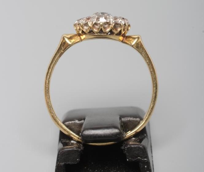 A NINE STONE DIAMOND CLUSTER RING, the old brilliant cut stones set to a plain shank stamped 18ct, Image