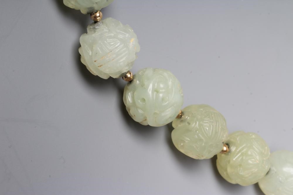 A STRING OF CHINESE CELADON JADE BEADS, the forty six spherical beads carved with scroll and Image
