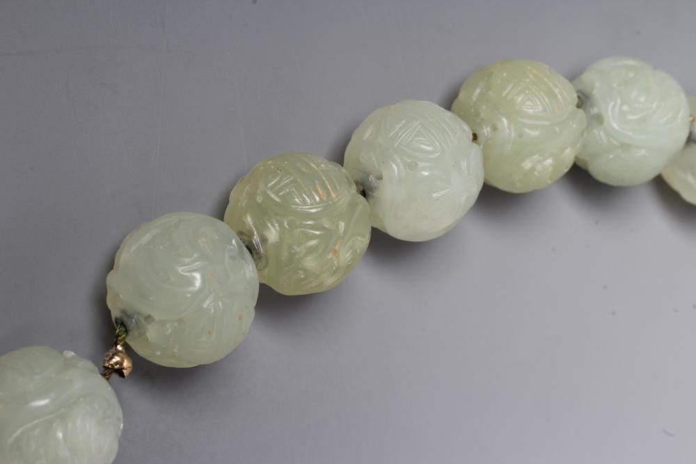 A STRING OF CHINESE CELADON JADE BEADS, the forty six spherical beads carved with scroll and Image
