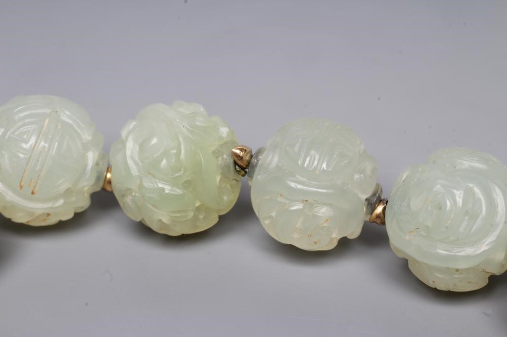 A STRING OF CHINESE CELADON JADE BEADS, the forty six spherical beads carved with scroll and Image