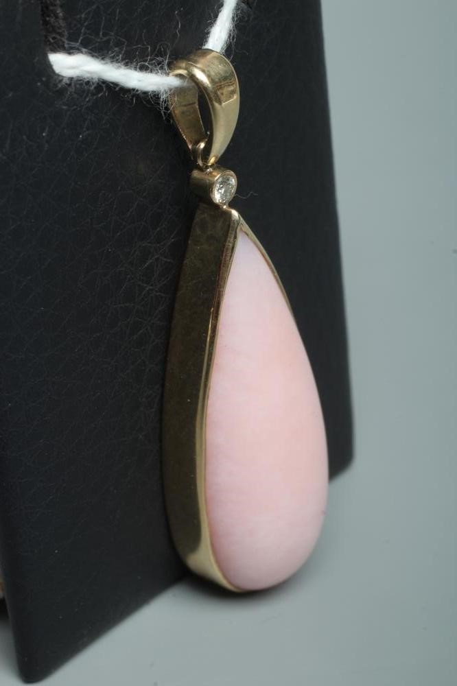 A PINK CHALCEDONY PENDANT, the shaped polished stone collet set in 9ct gold with a diamond point Image