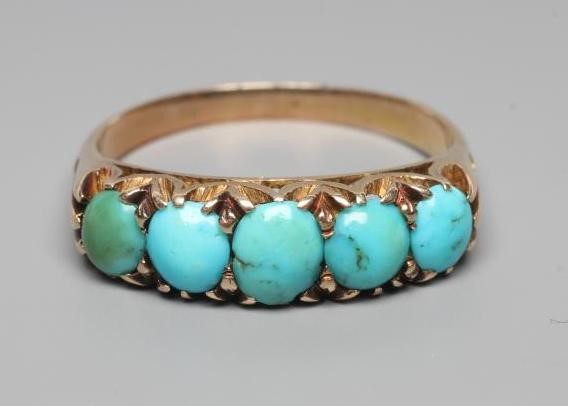 A LATE VICTORIAN TURQUOISE RING, the five oval cabochon polished stones claw set to open shoulders Image