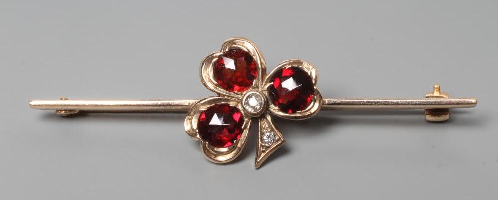 A SHAMROCK BAR BROOCH set with three facet cut circular garnets with small diamond centre and stem, Image