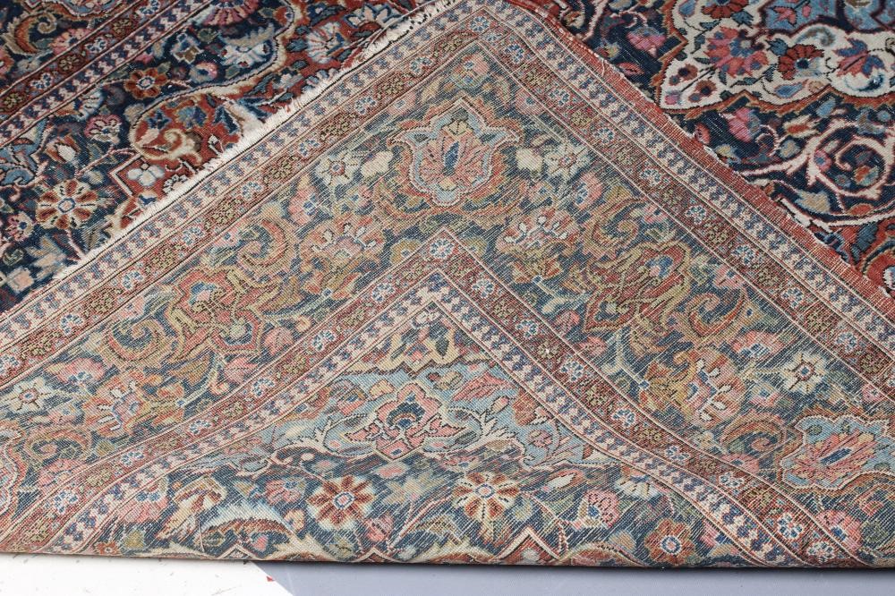 A PERSIAN RUG, the red floral field with navy blue and ivory gul, the navy blue main border with Image