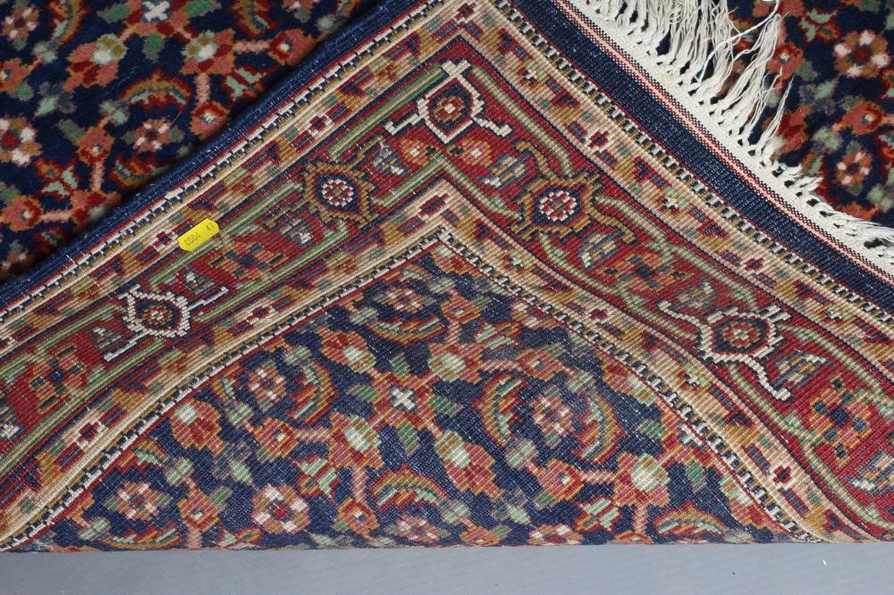 A PERSIAN RUG, the navy blue field with repeating pattern of foliate scrolls and flower heads, the Image