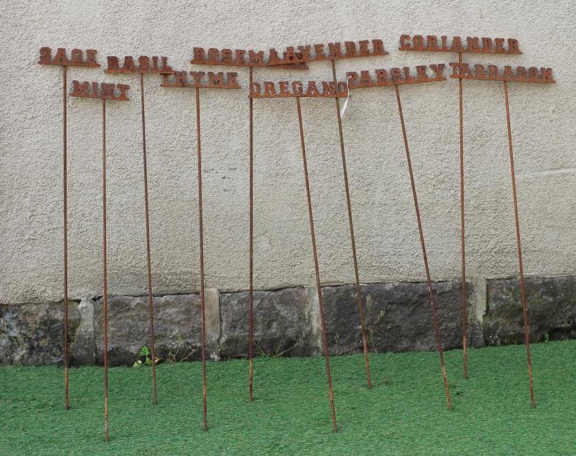 A SET OF TEN RECLAIMED METAL HERB LABELS, each on a turned post with rust patination, 6" - 13" x 37 Image