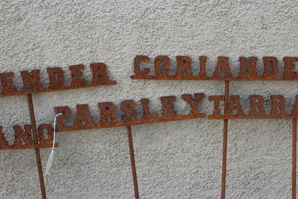 A SET OF TEN RECLAIMED METAL HERB LABELS, each on a turned post with rust patination, 6" - 13" x 37 Image