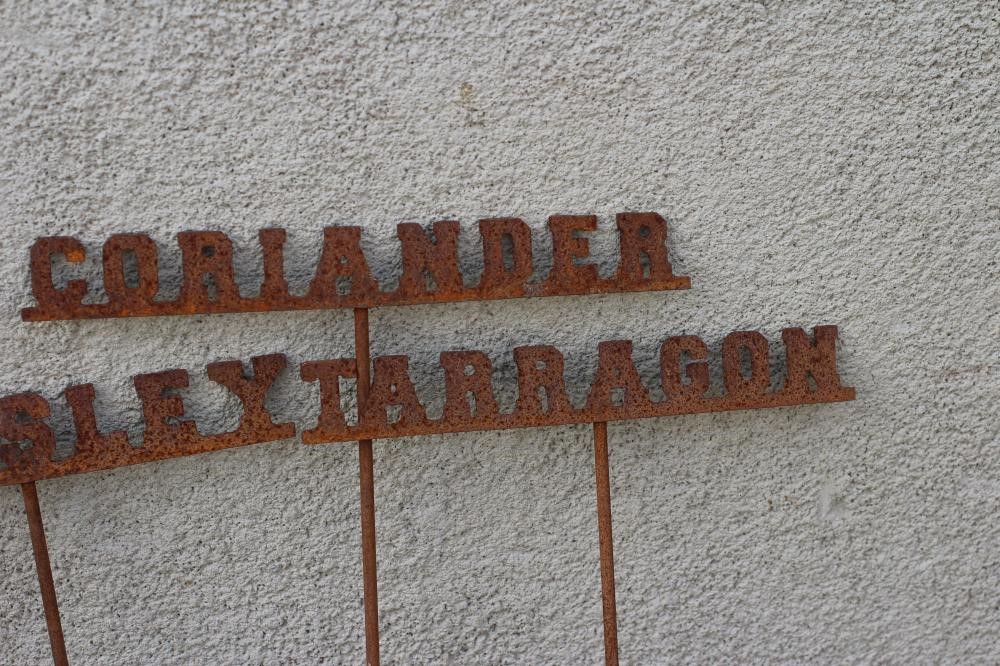 A SET OF TEN RECLAIMED METAL HERB LABELS, each on a turned post with rust patination, 6" - 13" x 37 Image