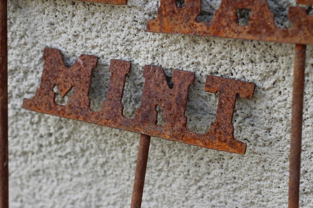 A SET OF TEN RECLAIMED METAL HERB LABELS, each on a turned post with rust patination, 6" - 13" x 37 Image