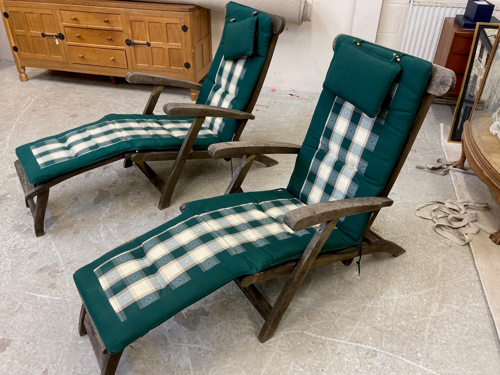 A PAIR OF SLATTED TEAK STEAMER ARMCHAIRS with brass fittings and green weather-proof loose cushions, Image
