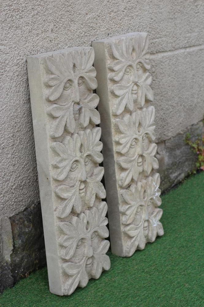 A PAIR OF CARVED SANDSTONE GREEN MAN WALL PANELS of oblong form each with three masks, 8" x 25" Image
