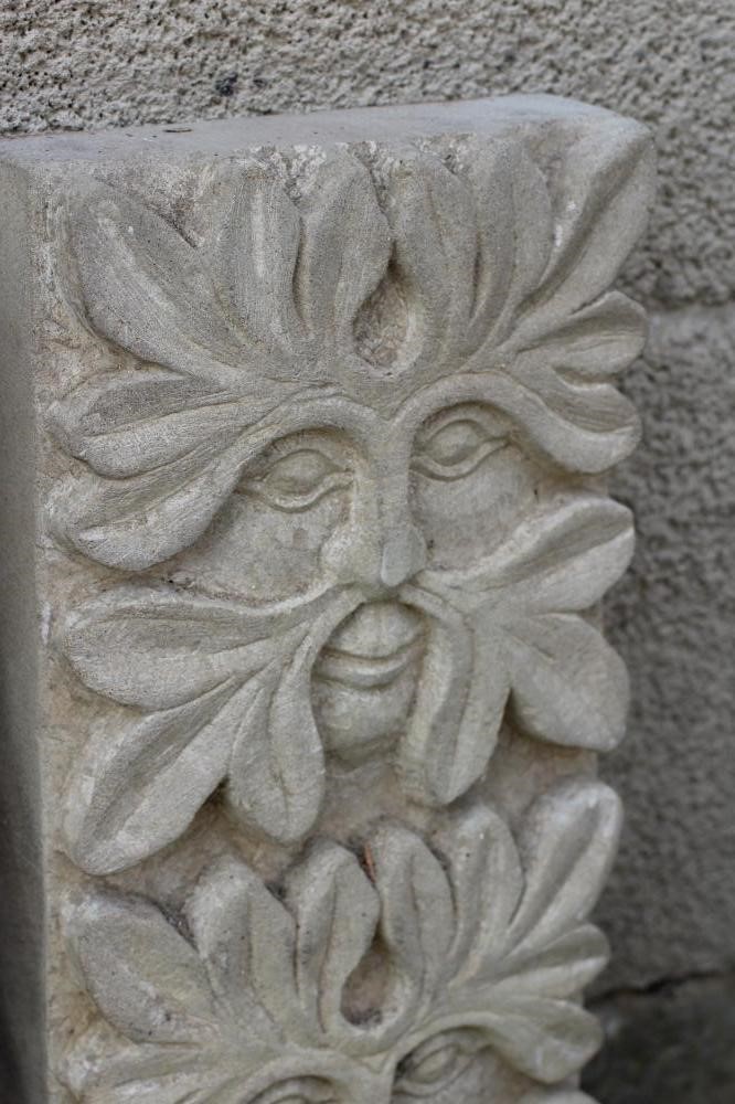 A PAIR OF CARVED SANDSTONE GREEN MAN WALL PANELS of oblong form each with three masks, 8" x 25" Image