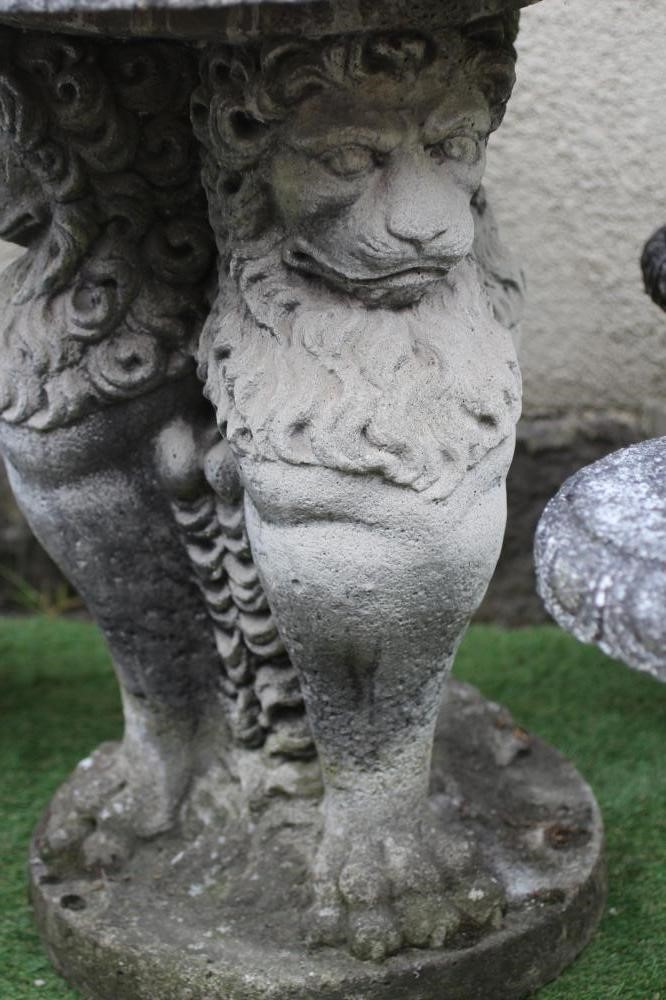 A CAST STONE TABLE, the circular top with ovolu rim on lion monopodiae supports and circular base, Image