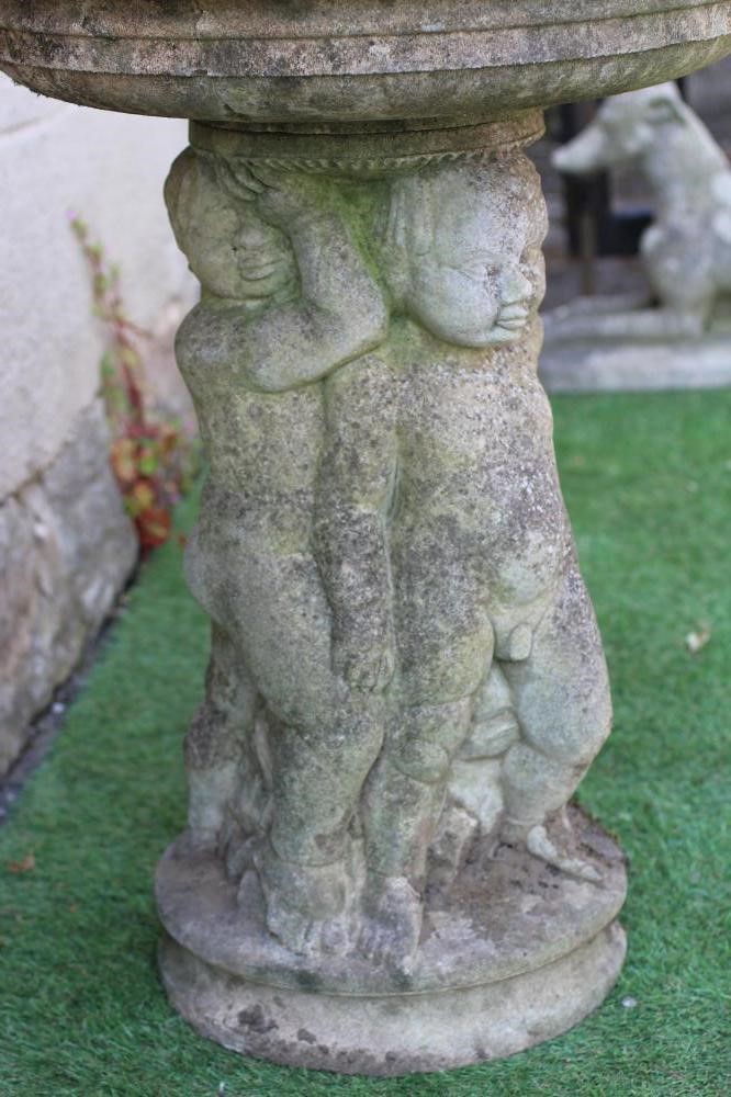 A HADDONSTONE BIRD BATH, the moulded circular bowl with ovolu rim held aloft by three putti, on Image
