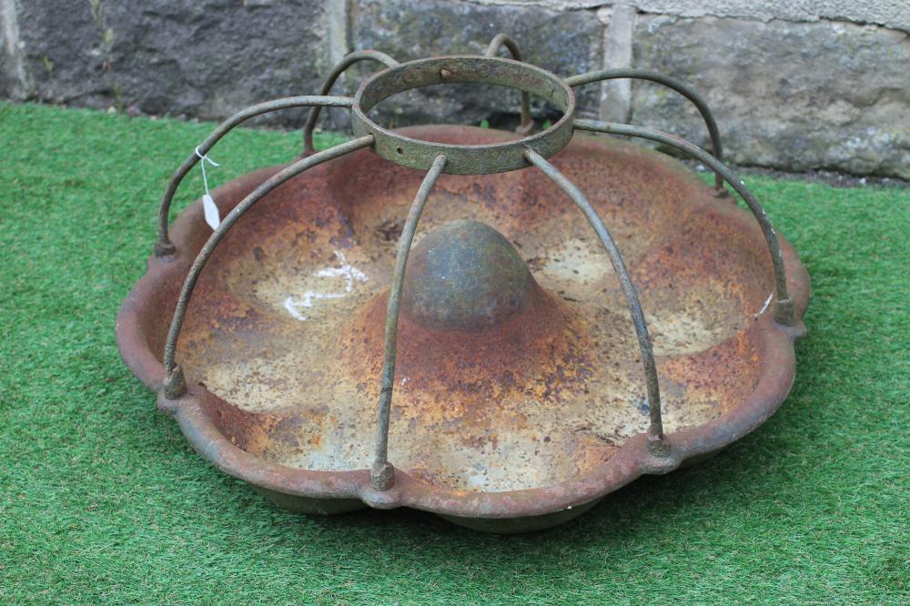 A CAST IRON PIG TROUGH, 20th century, of circular form with raised circular food aperture, 30" wide Image