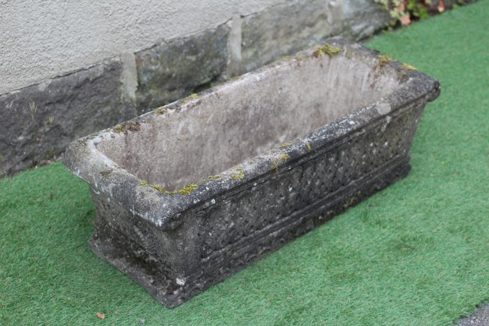 A CAST STONE JARDINIERE of oblong tapering form with scrolled rim and flared base, the sides moulded Image