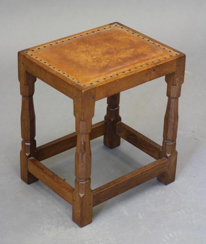 A ROBERT THOMPSON ADZED OAK STOOL of oblong form with padded cow hide seat Image