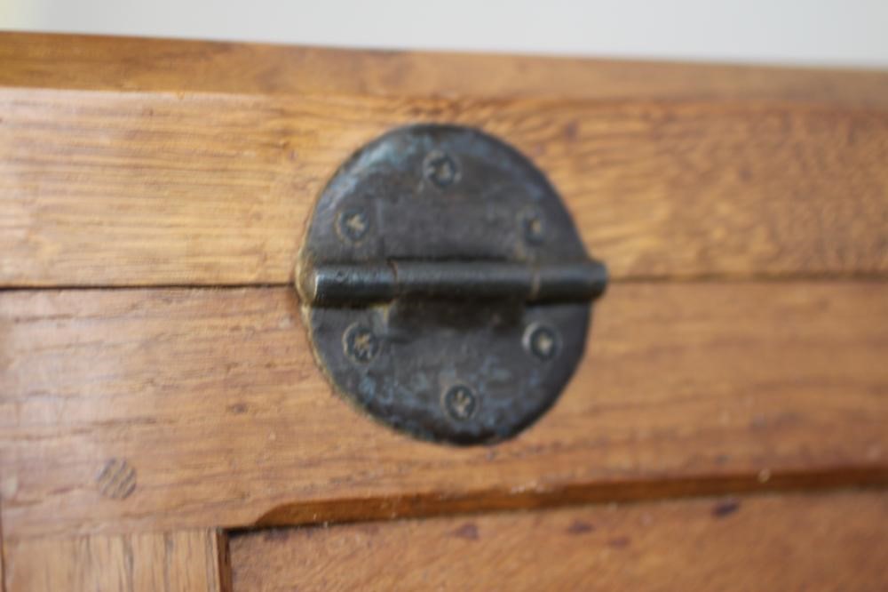 A ROBERT THOMPSON ADZED OAK BEDSIDE CABINET of canted multi-panelled oblong form Image