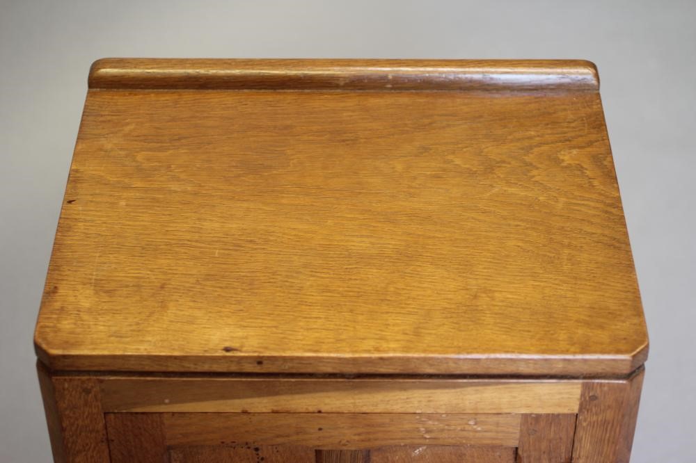 A ROBERT THOMPSON ADZED OAK BEDSIDE CABINET of canted multi-panelled oblong form Image