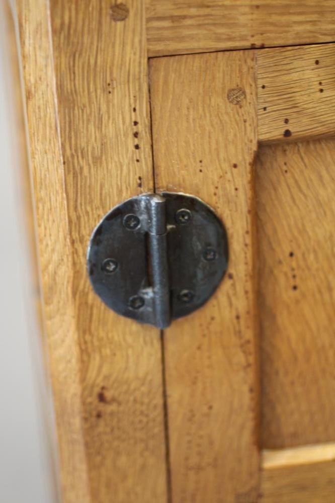 A ROBERT THOMPSON ADZED OAK BEDSIDE CABINET of canted multi-panelled oblong form Image