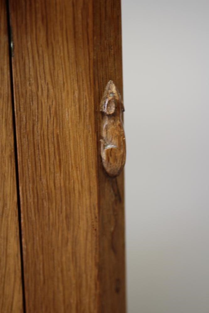 A ROBERT THOMPSON ADZED OAK BEDSIDE CABINET of canted multi-panelled oblong form Image