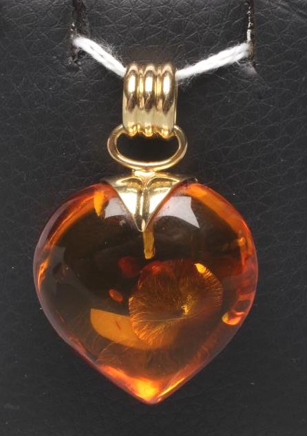A POLISHED AMBER HEART SHAPED PENDANT on 18ct gold mount and reeded bale (Est. plus 21% premium inc. Image