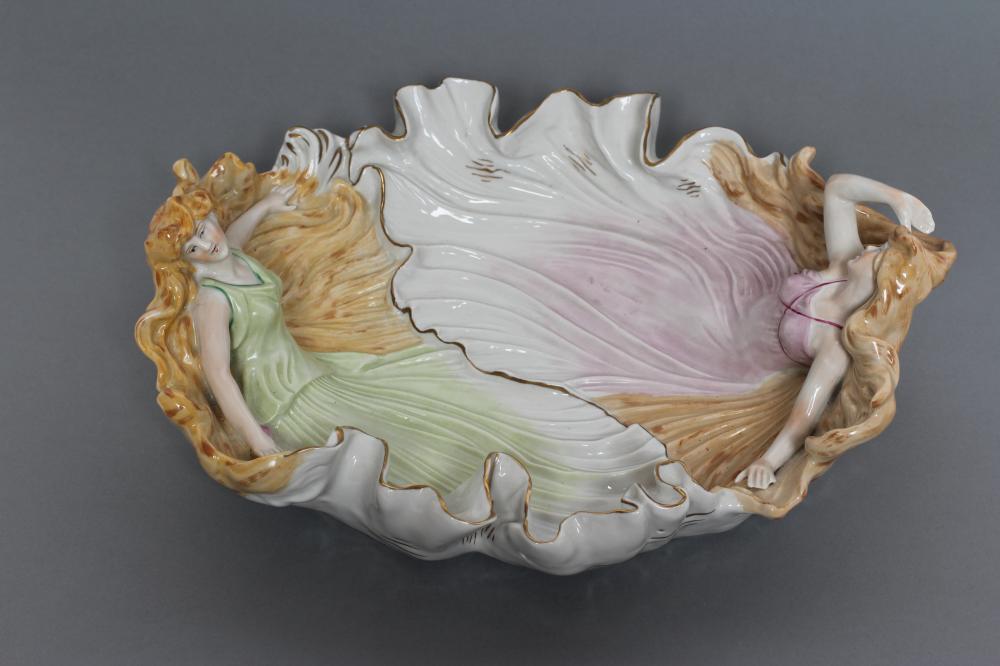A CONTINENTAL PORCELAIN CENTRE DISH modelled as two maidens wearing flowing green and pink tinted Image