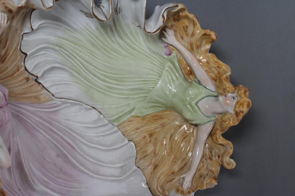A CONTINENTAL PORCELAIN CENTRE DISH modelled as two maidens wearing flowing green and pink tinted Image