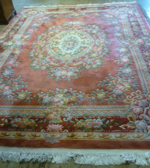 A CHINESE WASHED AND FRINGED AUBUSSON DESIGN CARPET with cream floral medallion and borders on a Image