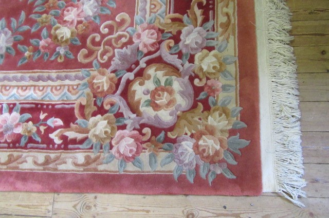A CHINESE WASHED AND FRINGED AUBUSSON DESIGN CARPET with cream floral medallion and borders on a Image