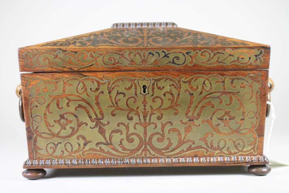 A REGENCY ROSEWOOD TEA CADDY of sarcophagus form with ring handles and raised upon four bun feet Image