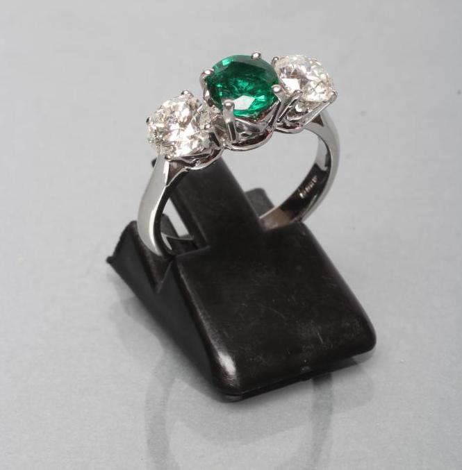 AN EMERALD AND DIAMOND THREE STONE RING Image