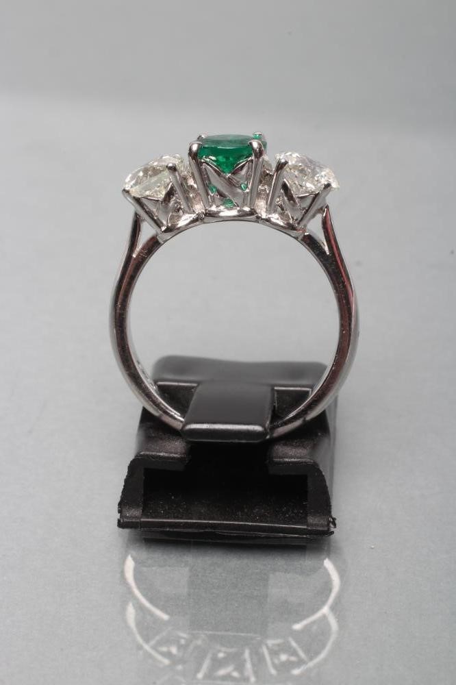 AN EMERALD AND DIAMOND THREE STONE RING Image