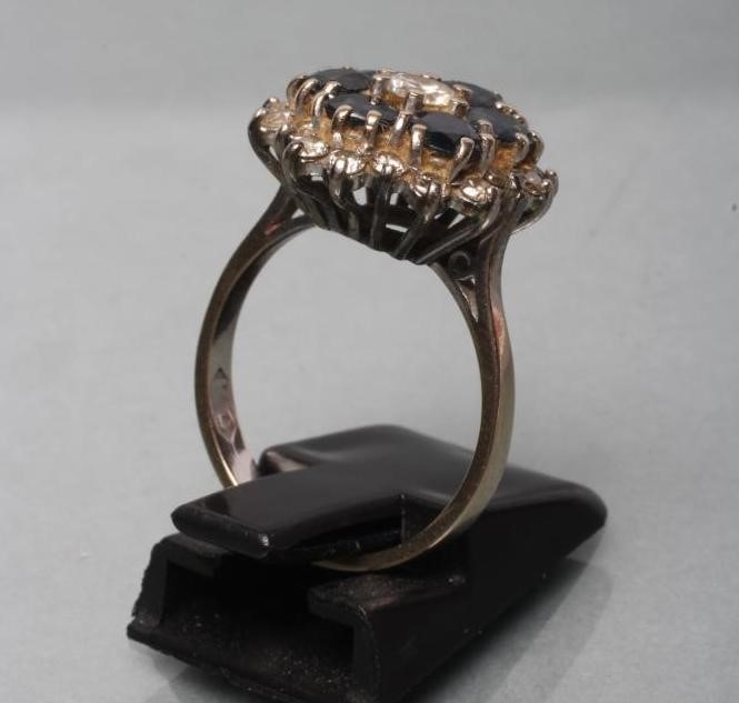 A SAPPHIRE AND DIAMOND CLUSTER RING claw set with six round facet cut claw set sapphires within a Image
