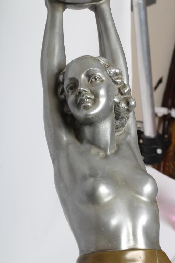 AFTER LORENZL - a large silvered metal figural lamp base modelled as a young female nude standing on Image