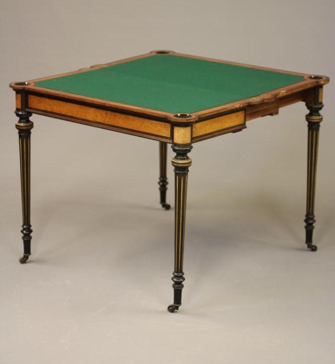A VICTORIAN AMBOYNA AND EBONISED FOLDING CARD TABLE of earred oblong form with gilt metal mounts Image