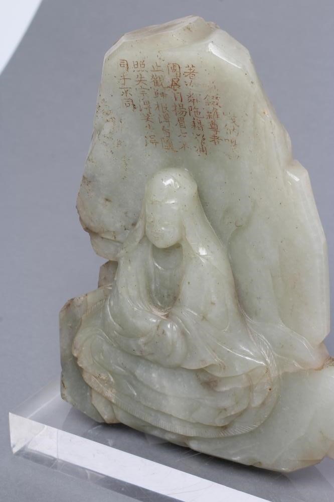 A CHINESE JADE DEITY seated before rockwork with engraved and stained red and gilt script Image