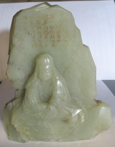 A CHINESE JADE DEITY seated before rockwork with engraved and stained red and gilt script Image
