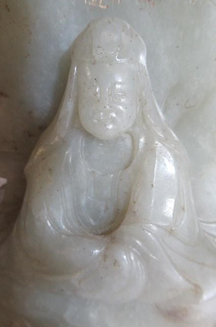 A CHINESE JADE DEITY seated before rockwork with engraved and stained red and gilt script Image