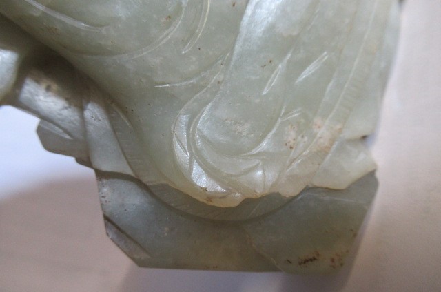 A CHINESE JADE DEITY seated before rockwork with engraved and stained red and gilt script Image