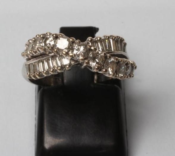 A DIAMOND RING crossover set with eleven graduated brilliant cut stones over fourteen small Image