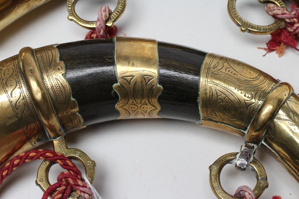 A MATCHED PAIR OF BRASS MOUNTED HORN POWDER FLASKS both with highly decorated metal work and twin Image