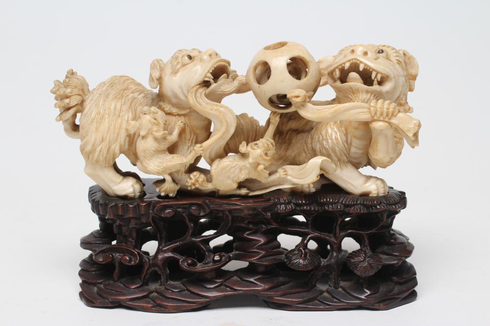 A CHINESE IVORY MODEL carved as a pair of Temple Dogs and their two puppies playing with a puzzle Image