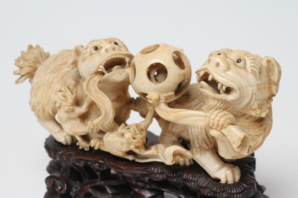 A CHINESE IVORY MODEL carved as a pair of Temple Dogs and their two puppies playing with a puzzle Image