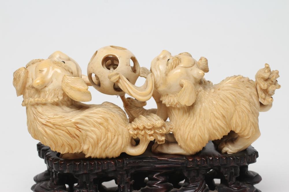 A CHINESE IVORY MODEL carved as a pair of Temple Dogs and their two puppies playing with a puzzle Image